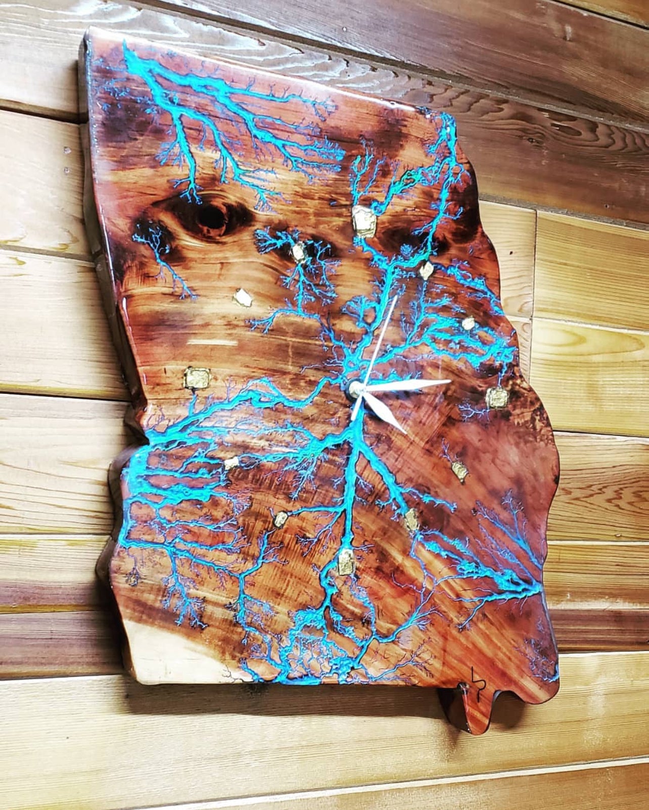 Wooden clock with blue resin inlay on a wooden surface